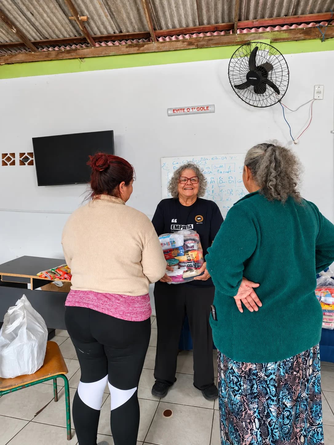 Voluntária do Nós na Rua entregando um kit de doações a famílias cadastradas no projeto Adote uma Família.