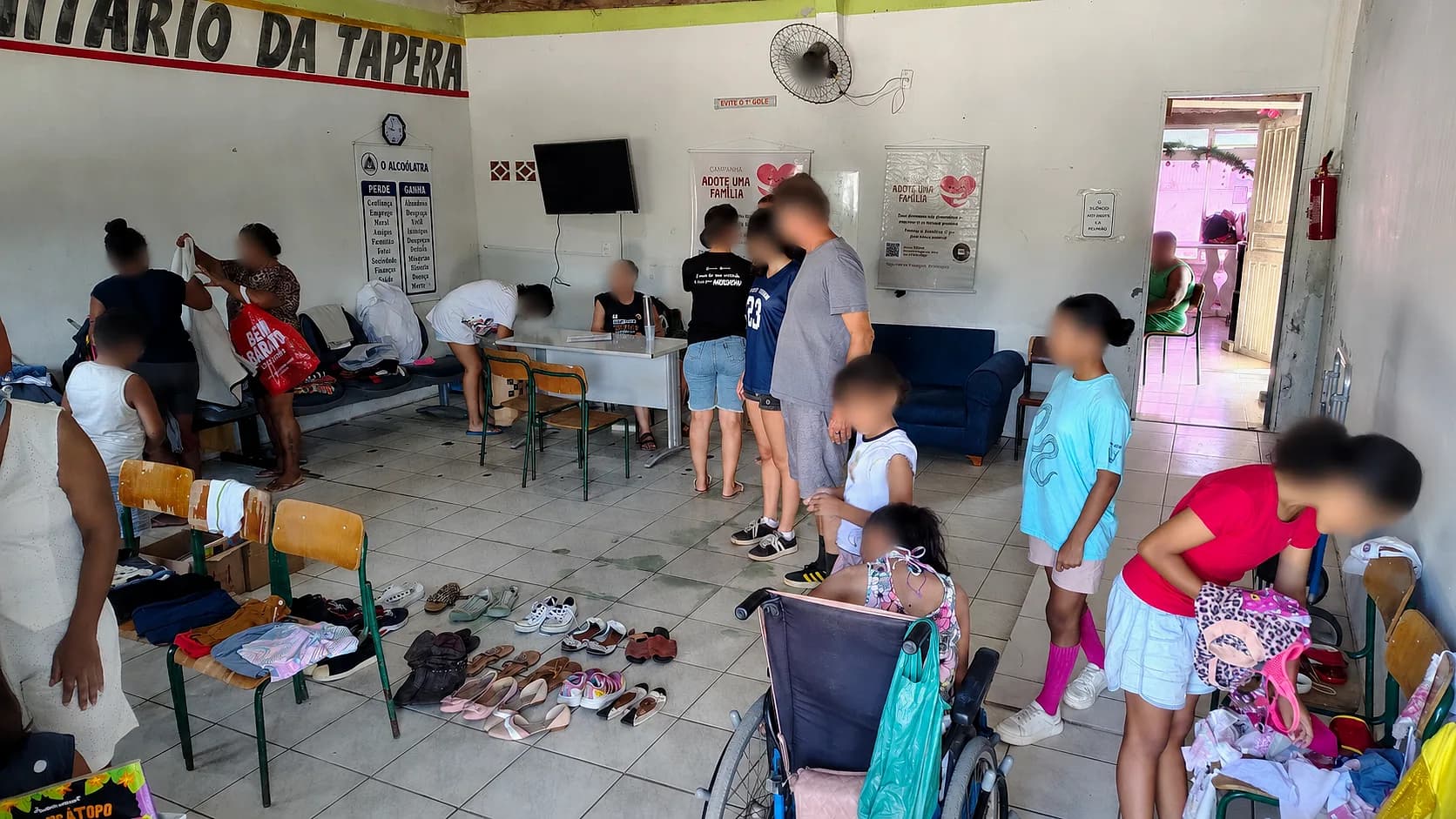 Voluntários e famílias durante ação comunitária na Tapera, com roupas e calçados organizados para doação.